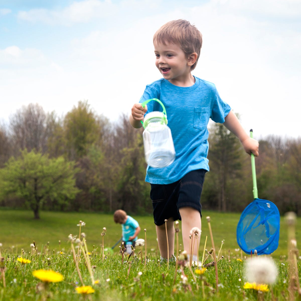 Young boy looking for bugs with a jar and net